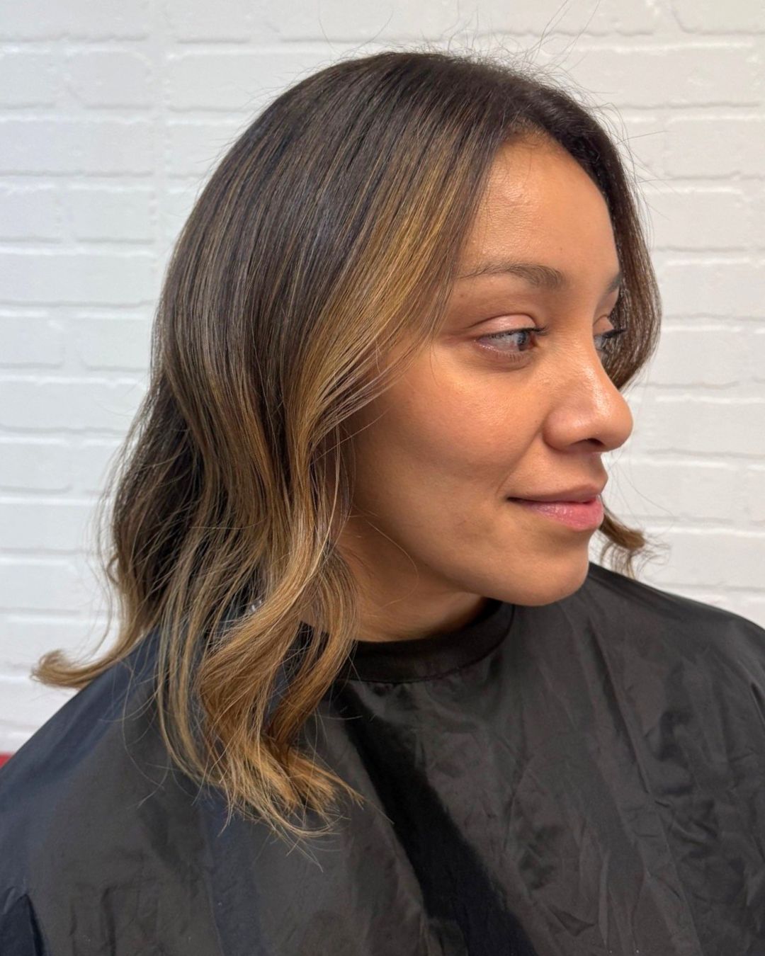 Soft face-framing highlights on dark brunette hair