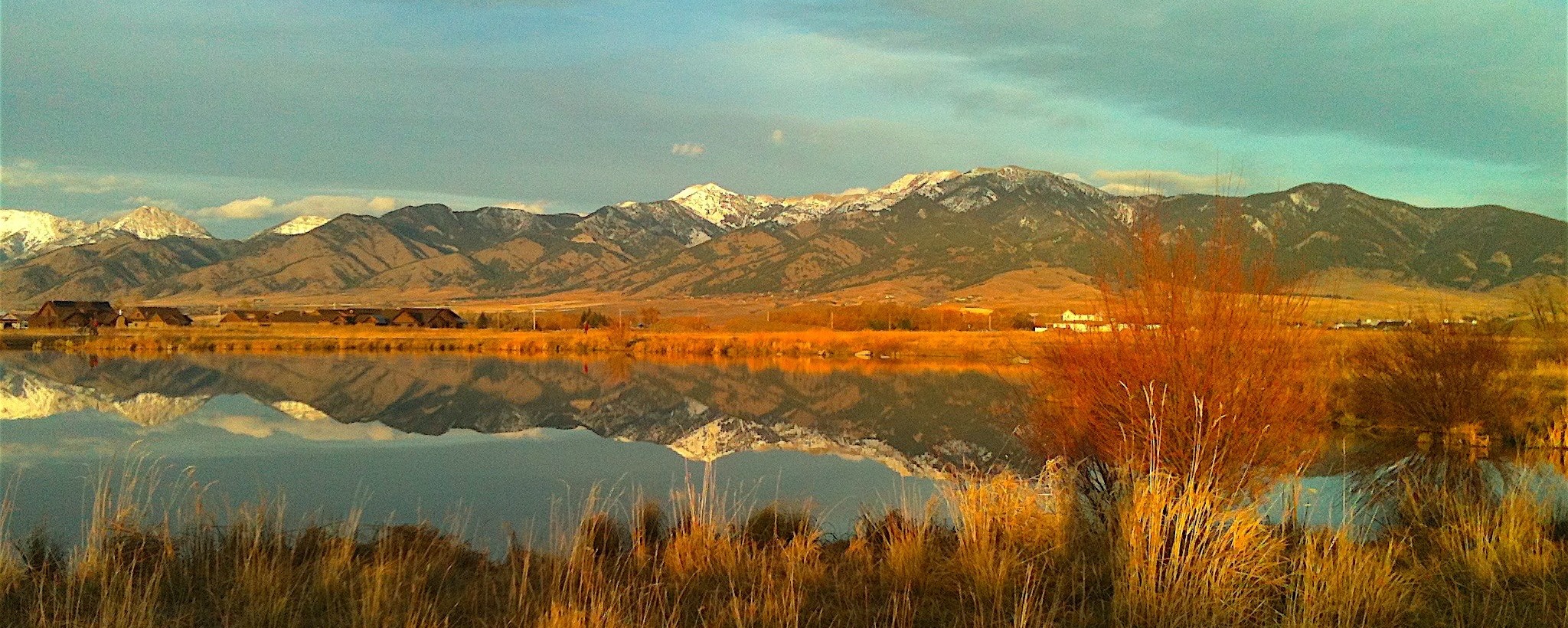 Snow-capped Montana mountains reflected in a still lake at golden hour