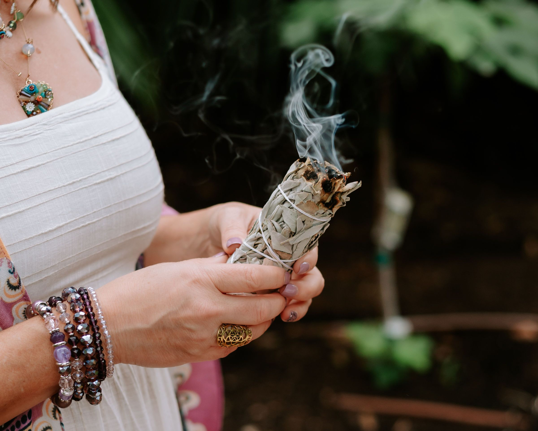 A Sacred Burning Bundle of Sage with Woman's Hands Wearing Jewelry