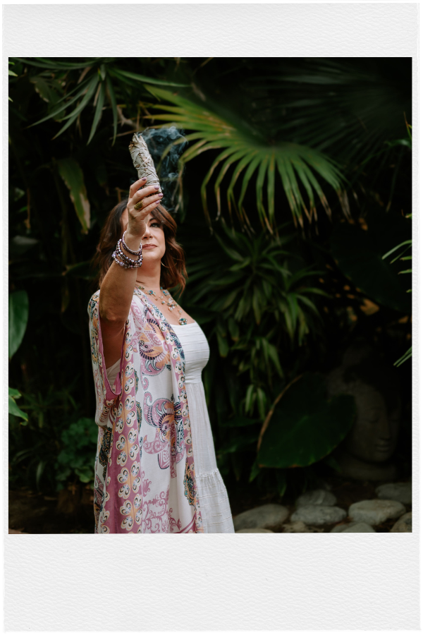 Ashley Levin in front of Palm Tree Holding a Burning Bundle of Sage
