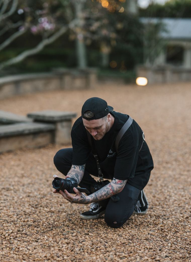 Josh crouched on a gravel path checking shots on his camera