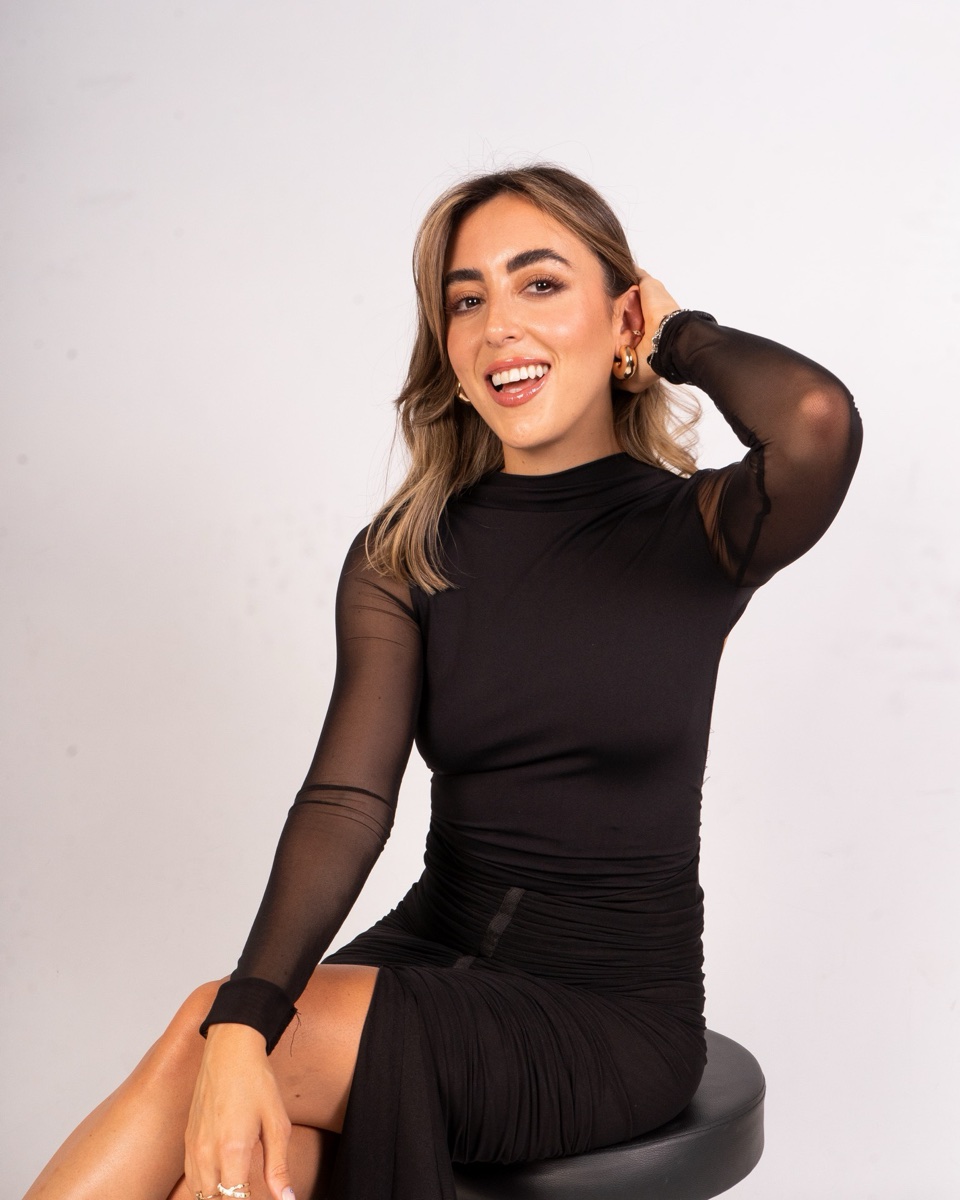 Gabriela Ferrando, nutricionista, sentada en un banco con vestido negro