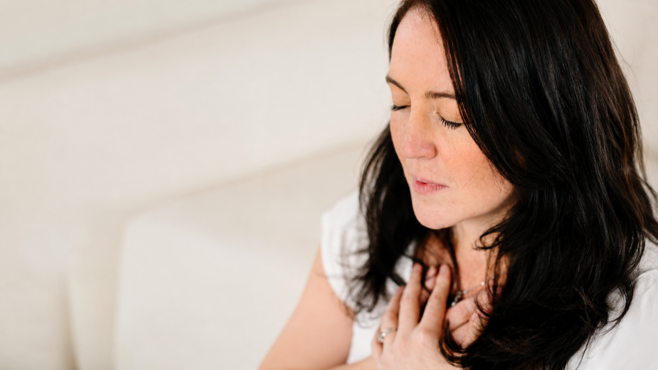 Woman with eyes closed and hands over her chest during anxiety after betrayal