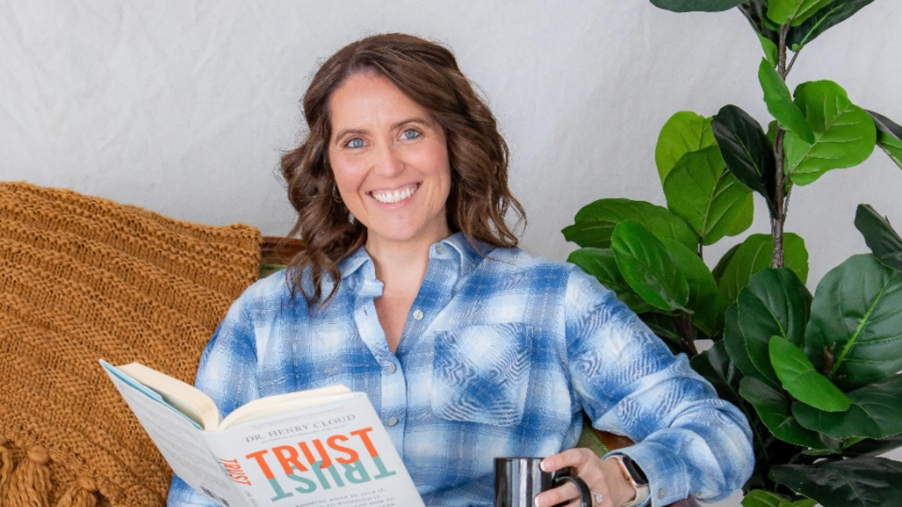 Carrie sitting on a couch reading a book about trust