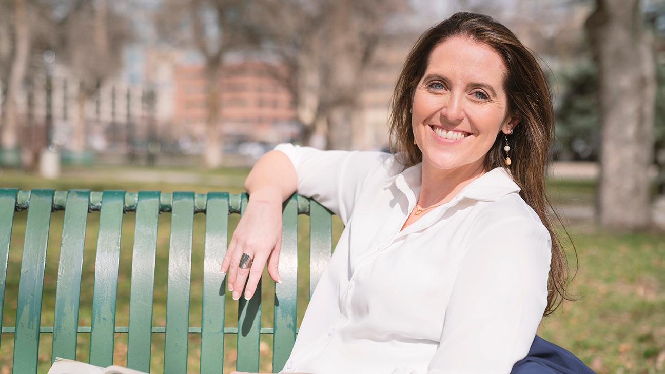Carrie sitting outside on a bench with a book in hand