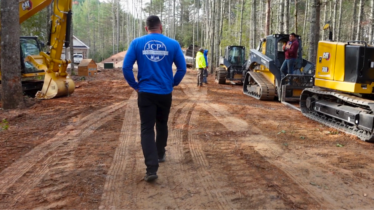 John Seaman walking down road lined with heavy equipment.