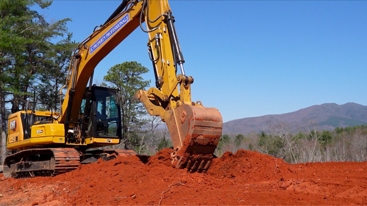 JC Property Professionals 317 CAT excavator moving dirt.