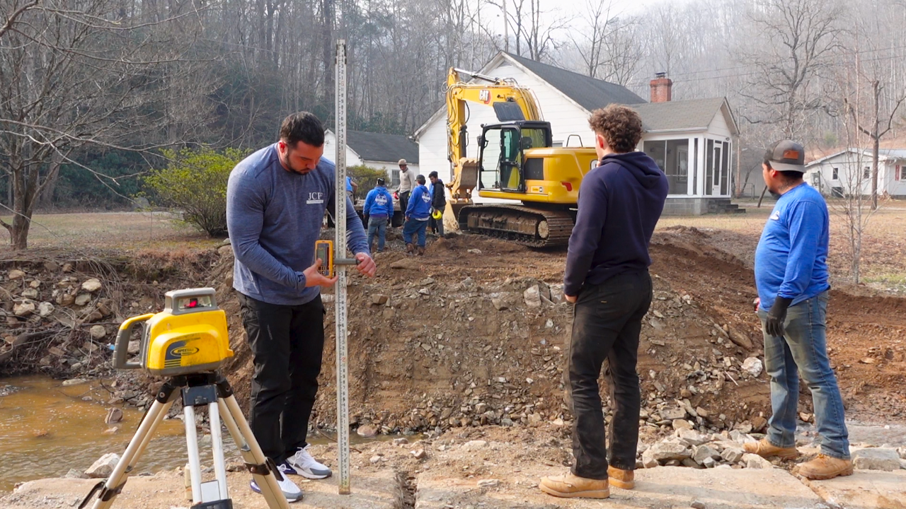 John Seaman using laser level on excavation job with crew.