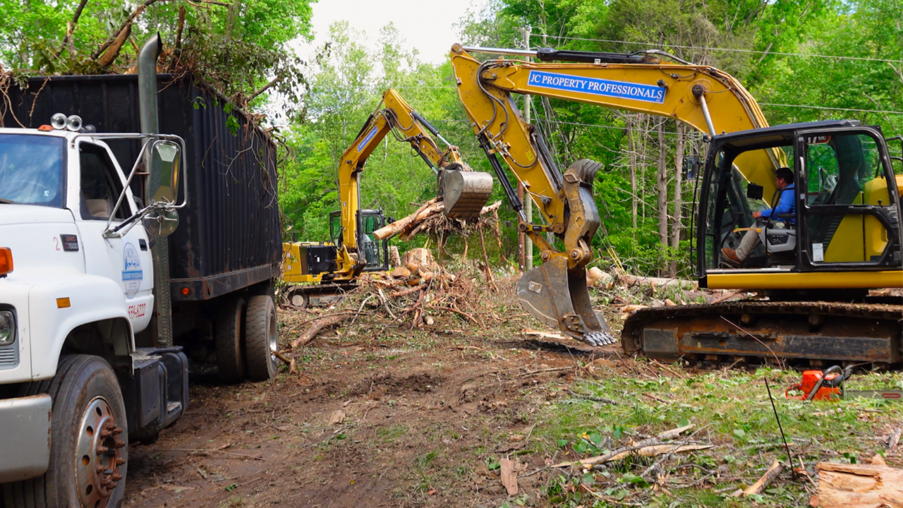 excavator and dump truck clearing land and loading debris on a job site