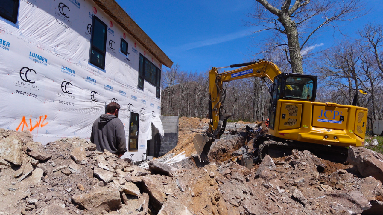 Project manager and operator working with an excavator on a residential construction site
