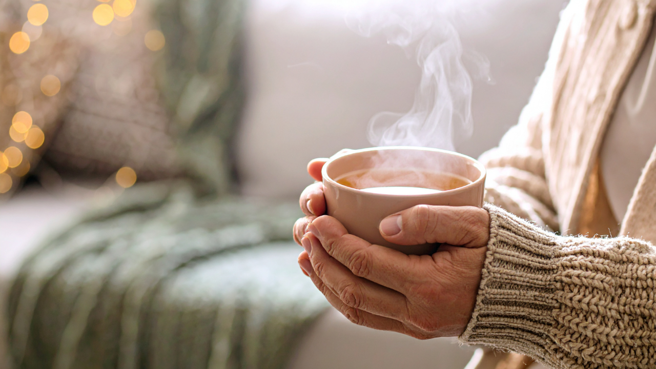 Hands cupping a warm mug to represent self-care and rest