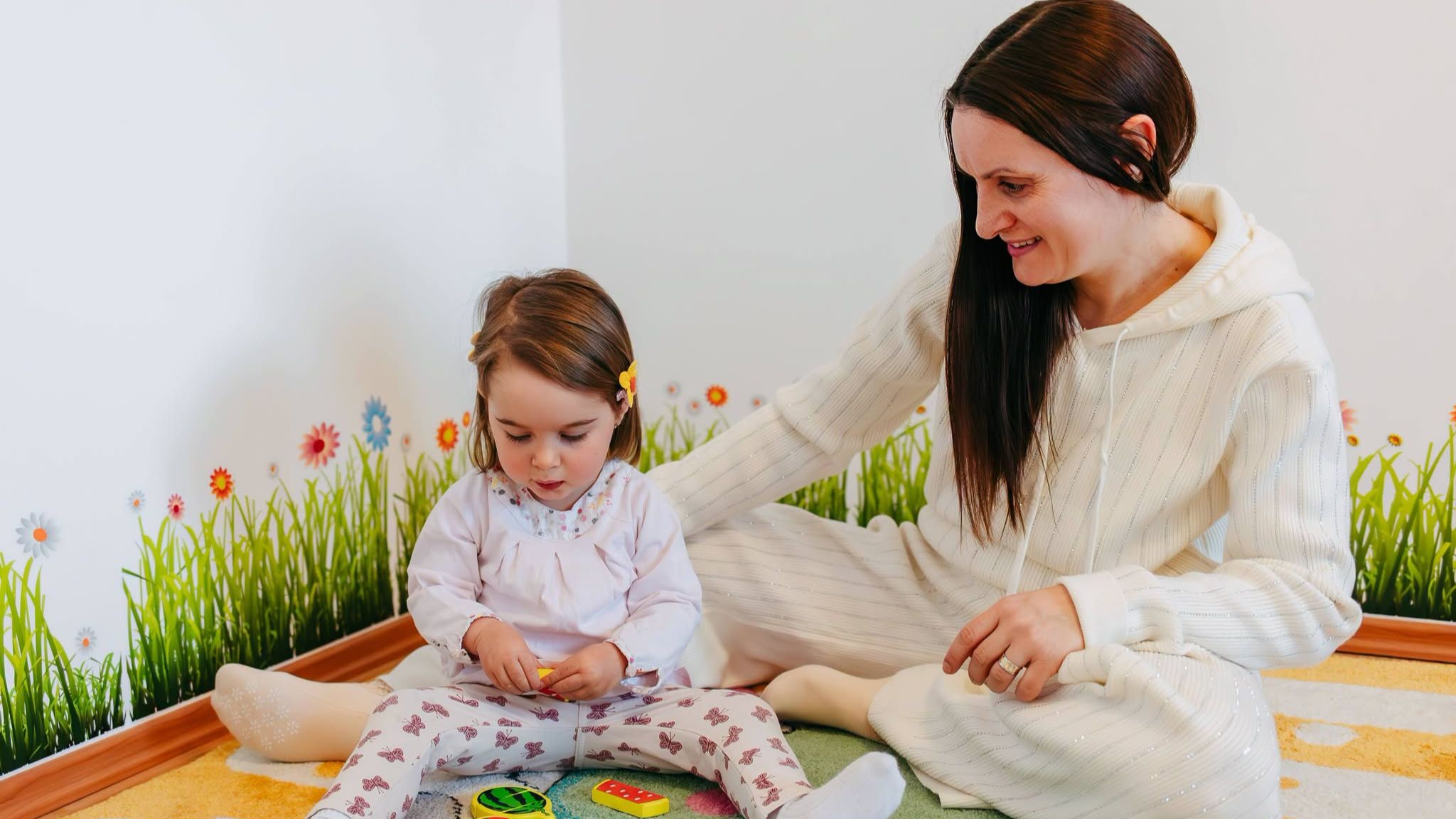 Mamă care se joacă împreună cu copilul folosind jucării educaționale pentru dezvoltarea limbajului și comunicării acasă.