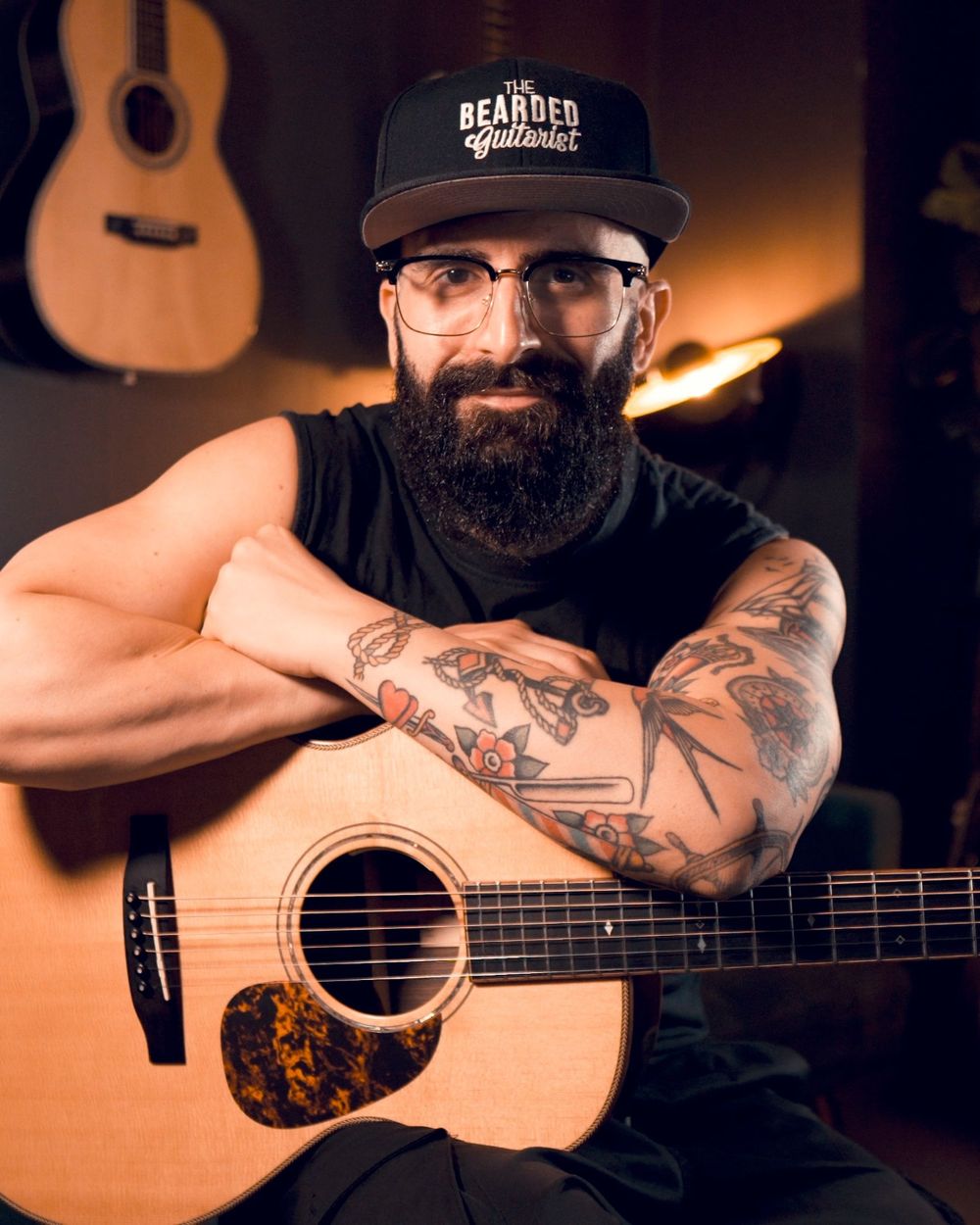 Simone, The Bearded Guitarist, smiling with his acoustic guitar in his studio