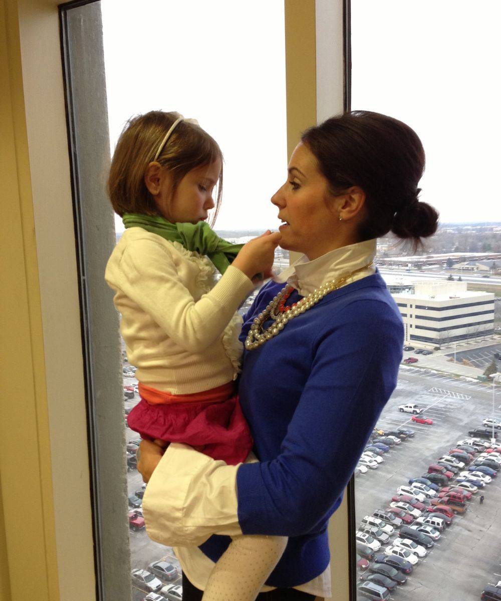 Tiffany holding her young daughter at an office window.