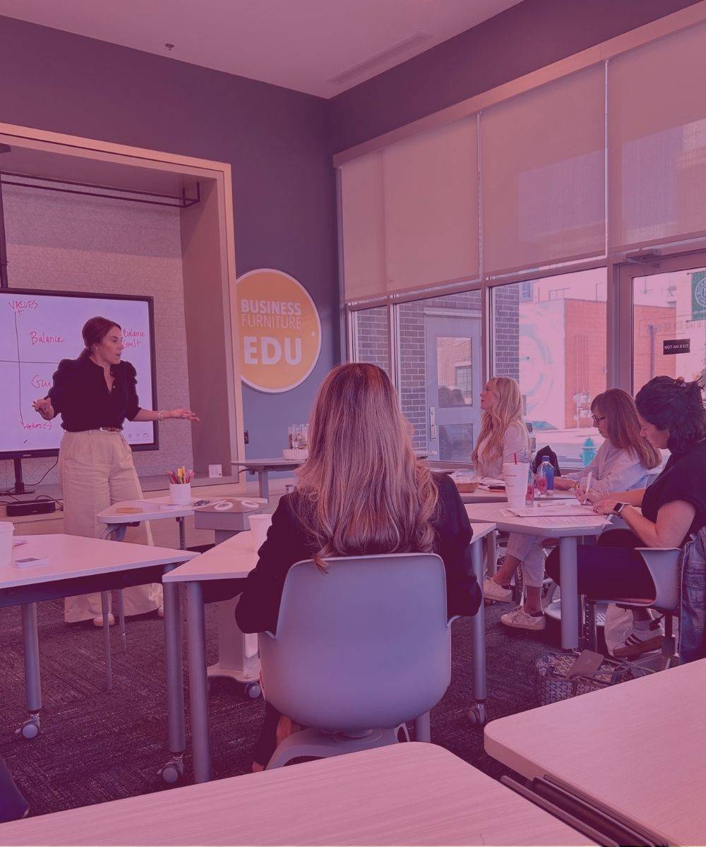 Tiffany Sauder presenting at the front of a classroom while women seated at tables follow along.