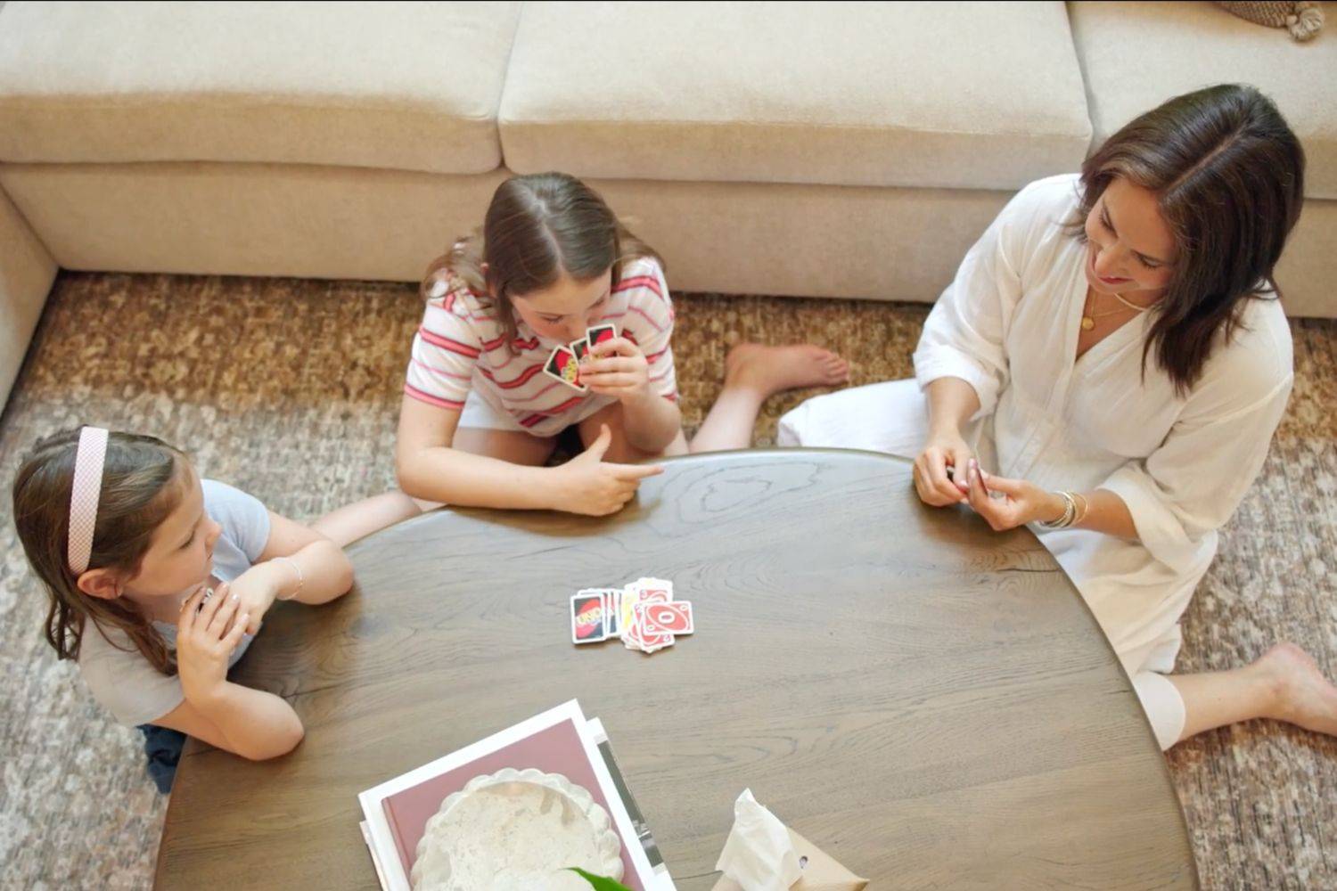 Tiffany playing cards with two of her daughters around the living room coffee table.