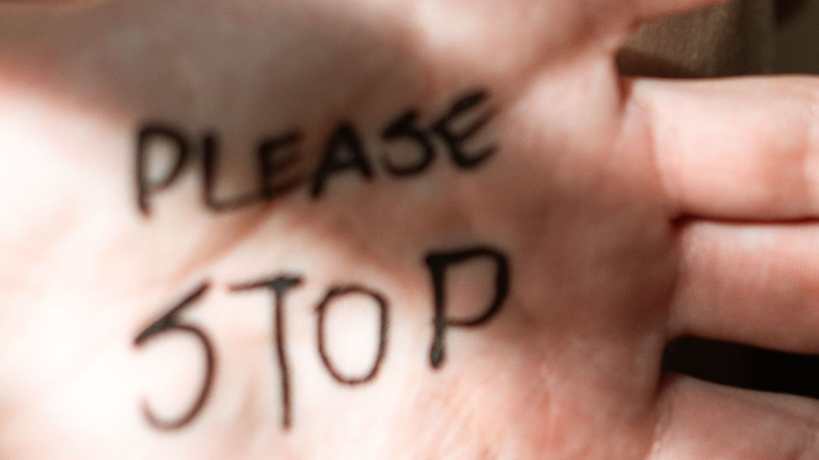 Close-up of a hand with "Please Stop" written on the palm, symbolising boundaries and accountability in relationships