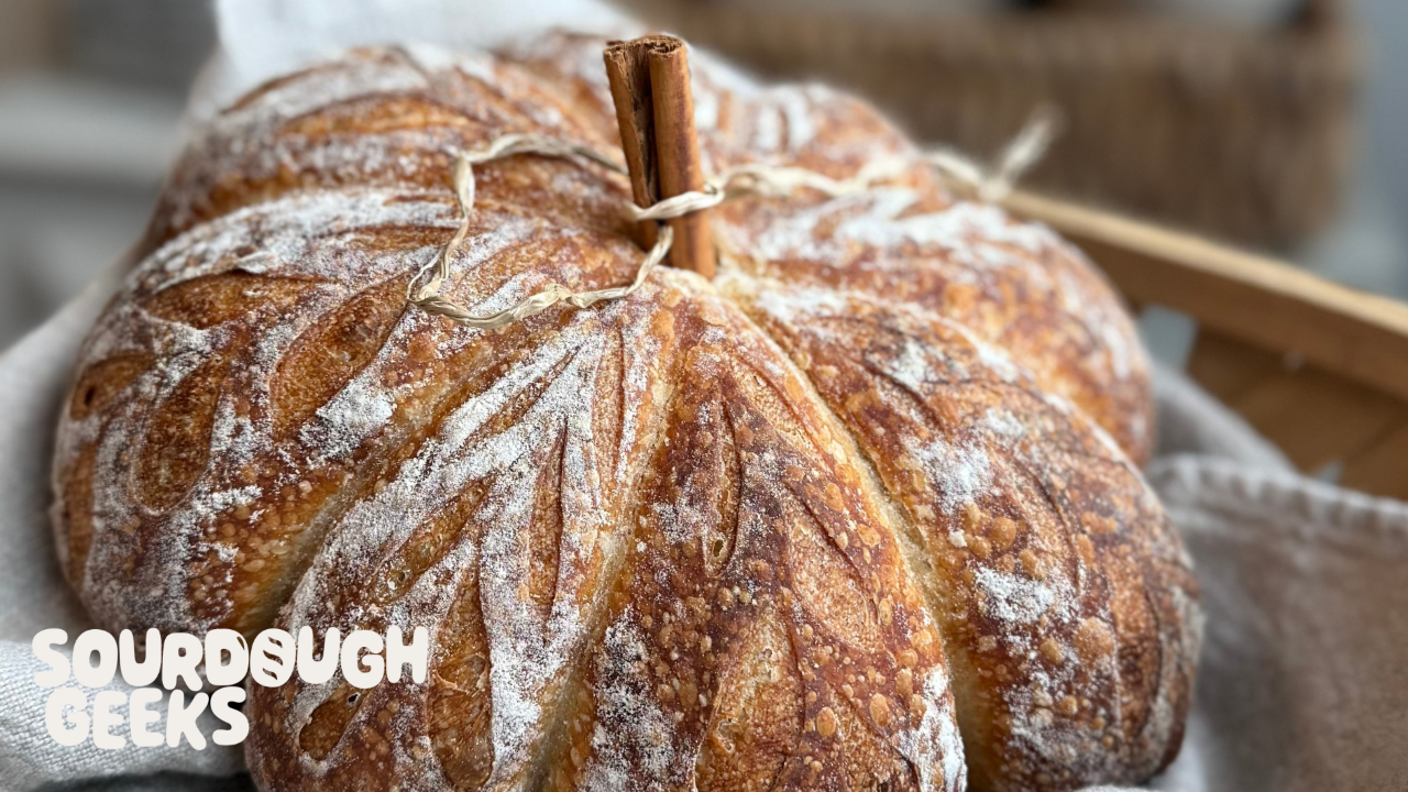 a loaf on sourdough that is shaped like a pumpkin and is prettily scored