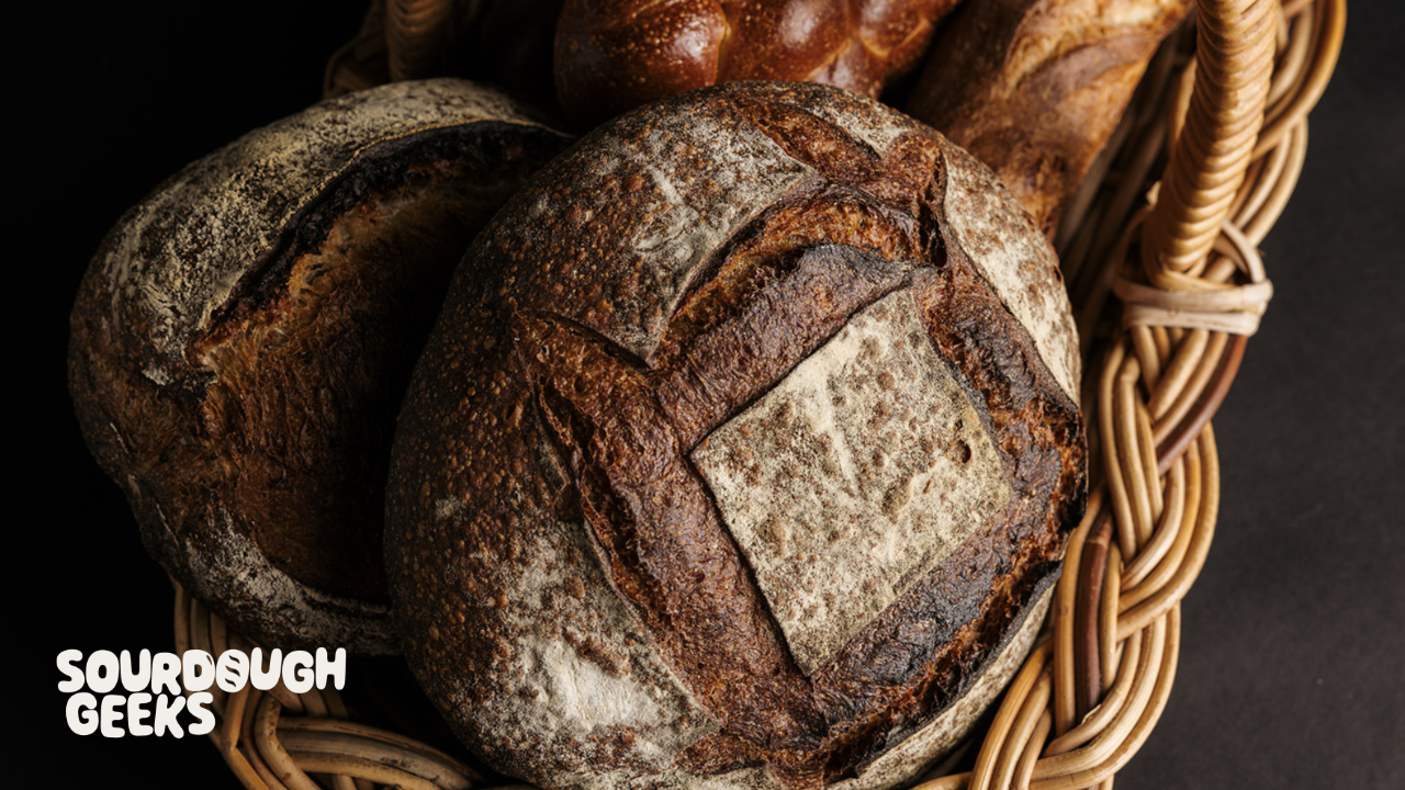 a moody overhead shot of bold baked artisan loaves in a basket, baked by The Grainwright. 