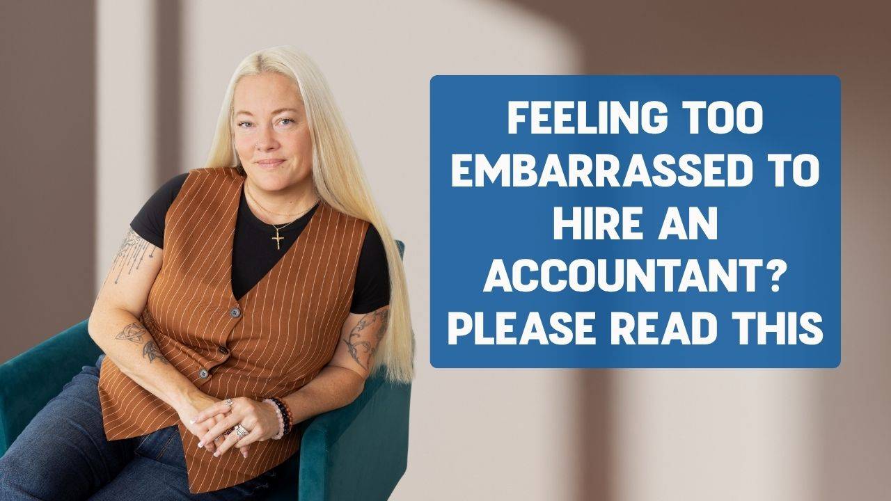Blonde woman sitting on a turquoise arm chair wearing blue jeans, a black shirt and a brown stripped vest resting her elbow on the arm chair and words on the screen that say," When Embarrassment Stops You From Hiring an Accountant, Please Read This"