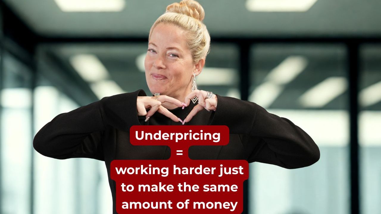 Woman wearing a black long sleeve shirt making a heart shape with her hands and smiling with words on the screen that say, "Underpricing = working harder just to make the same amount of money"