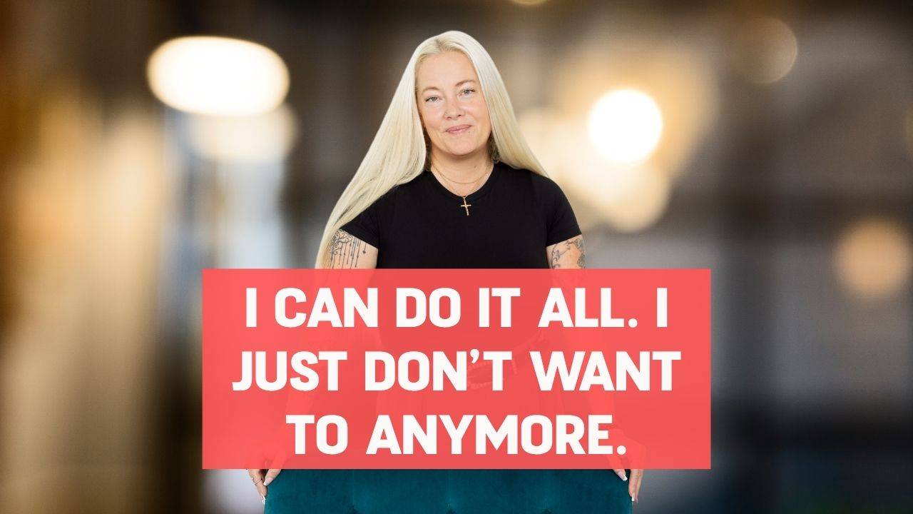 Blonde woman in a black shirt smiling and standing behind a turquoise arm chair with words on the screen that say, "I Can Do It All. I Just Don’t Want to Anymore."