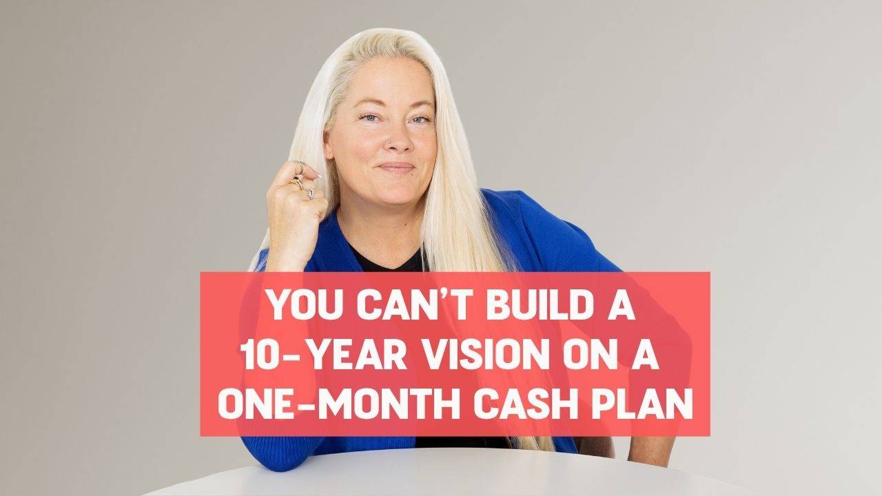 Blonde woman wearing a black shirt and blue blazer with her elbow propped up on a white round table and words on the screen that say, "You Can’t Build a 10-Year Vision on a One-Month Cash Plan"