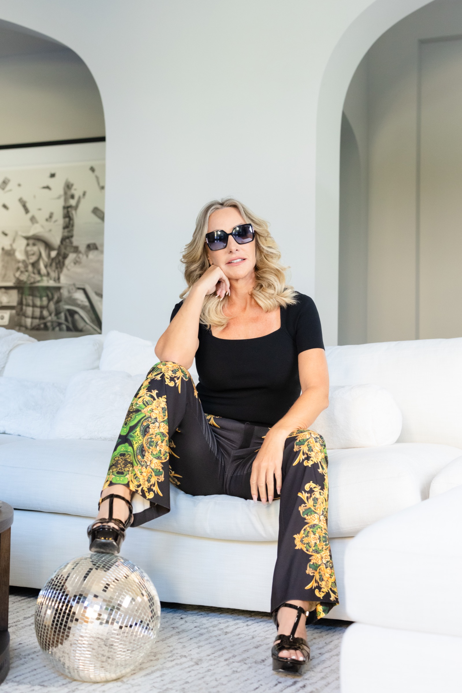 Brooke Hicks wearing sunglasses, seated on a white couch