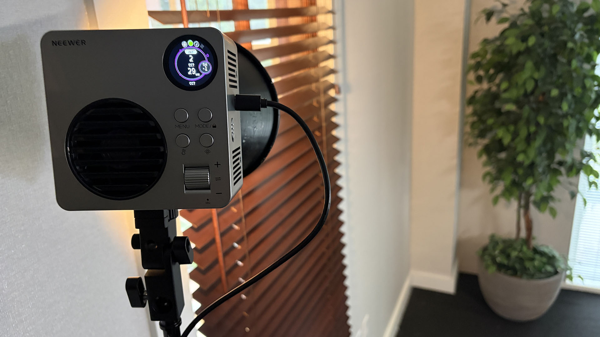 Compact Neewer HB80C positioned near the warm interior window and background plant