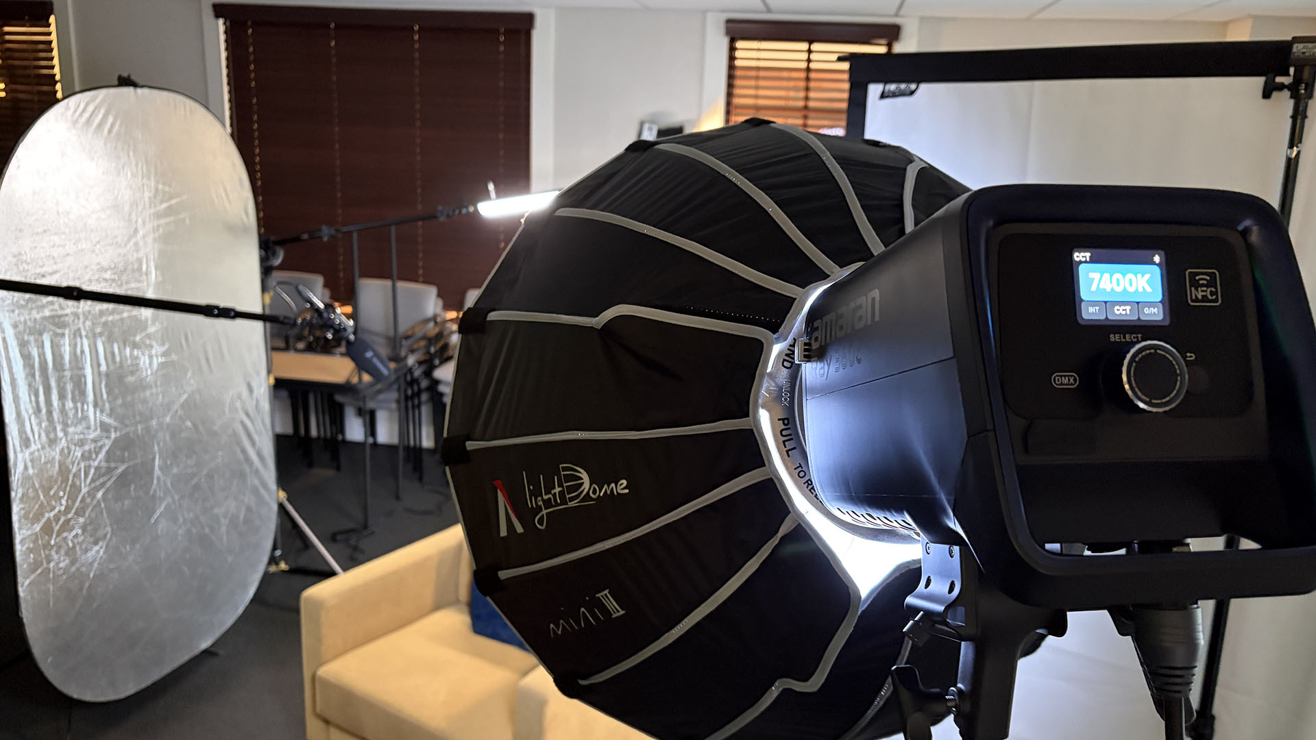 Amaran 360c key light display set to 7400 Kelvin beside the interview chair and silver bounce
