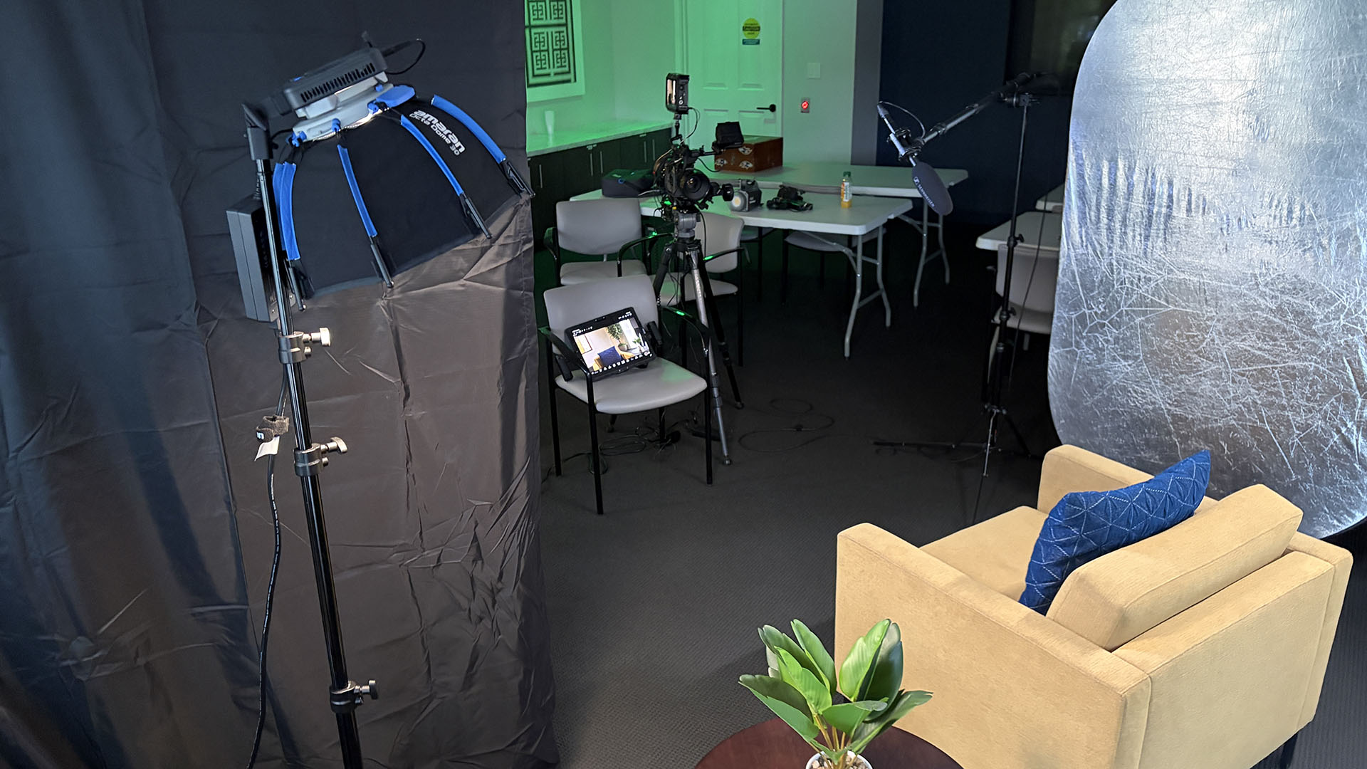 Wide behind-the-scenes view of the key, large black floppy, and silver fill bounce around the interview chair