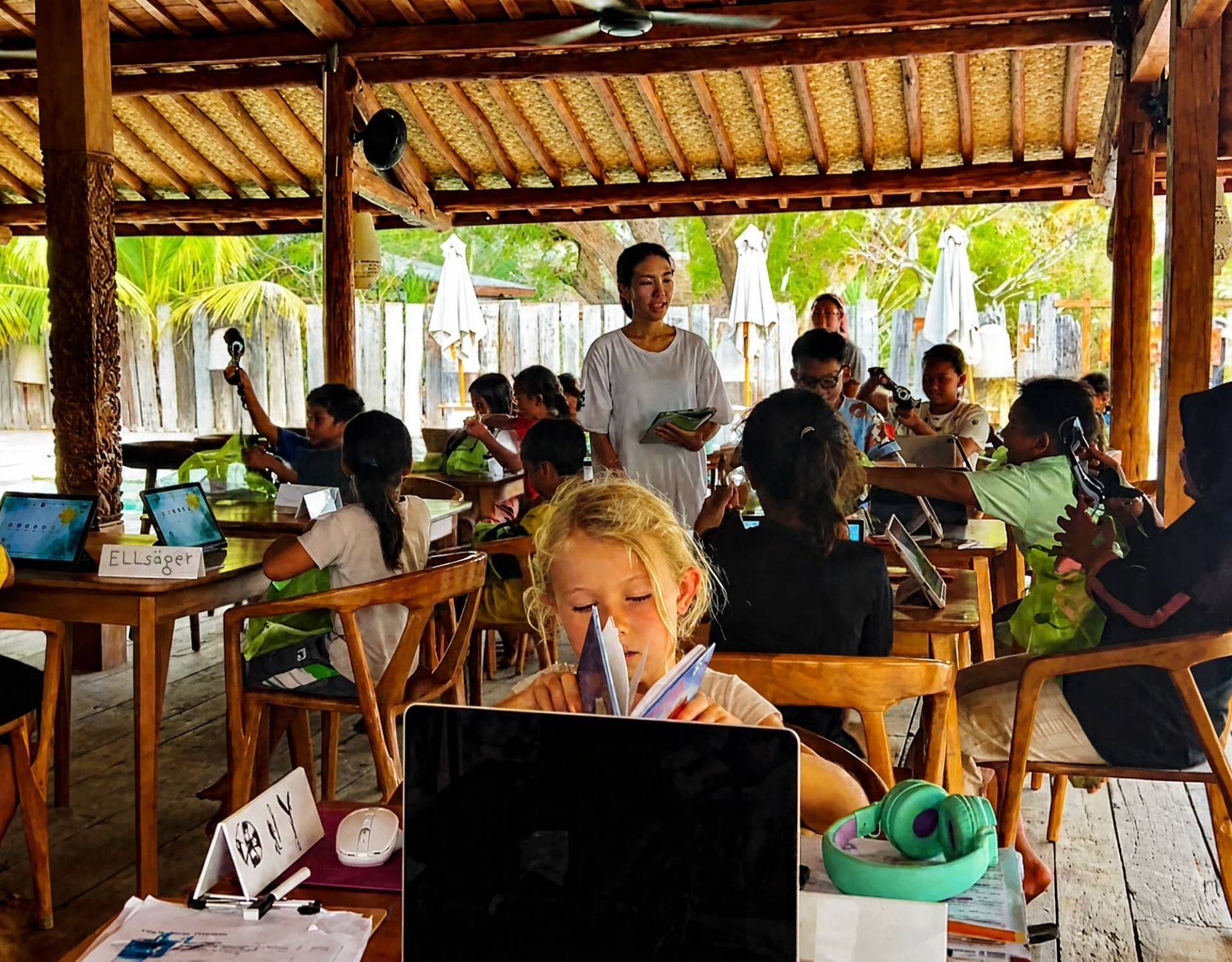 Students reading and using laptops in an outdoor school