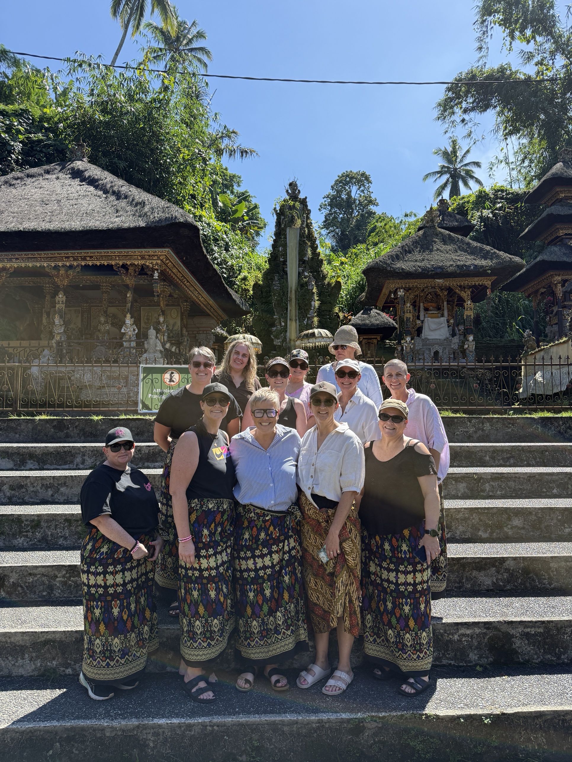 Women's group at a Balinese temple wearing traditional sarongs during RECHARGE retreat excursion