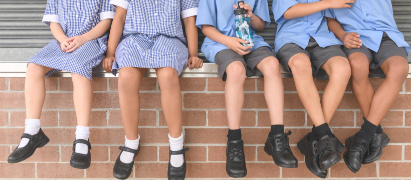 Children in school uniform sitting on a wall