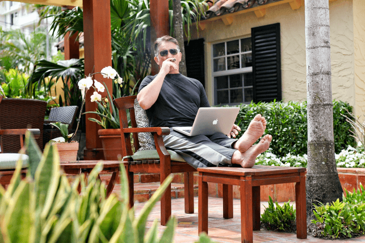 Mark Ford relaxing outdoors on a patio chair with a laptop
