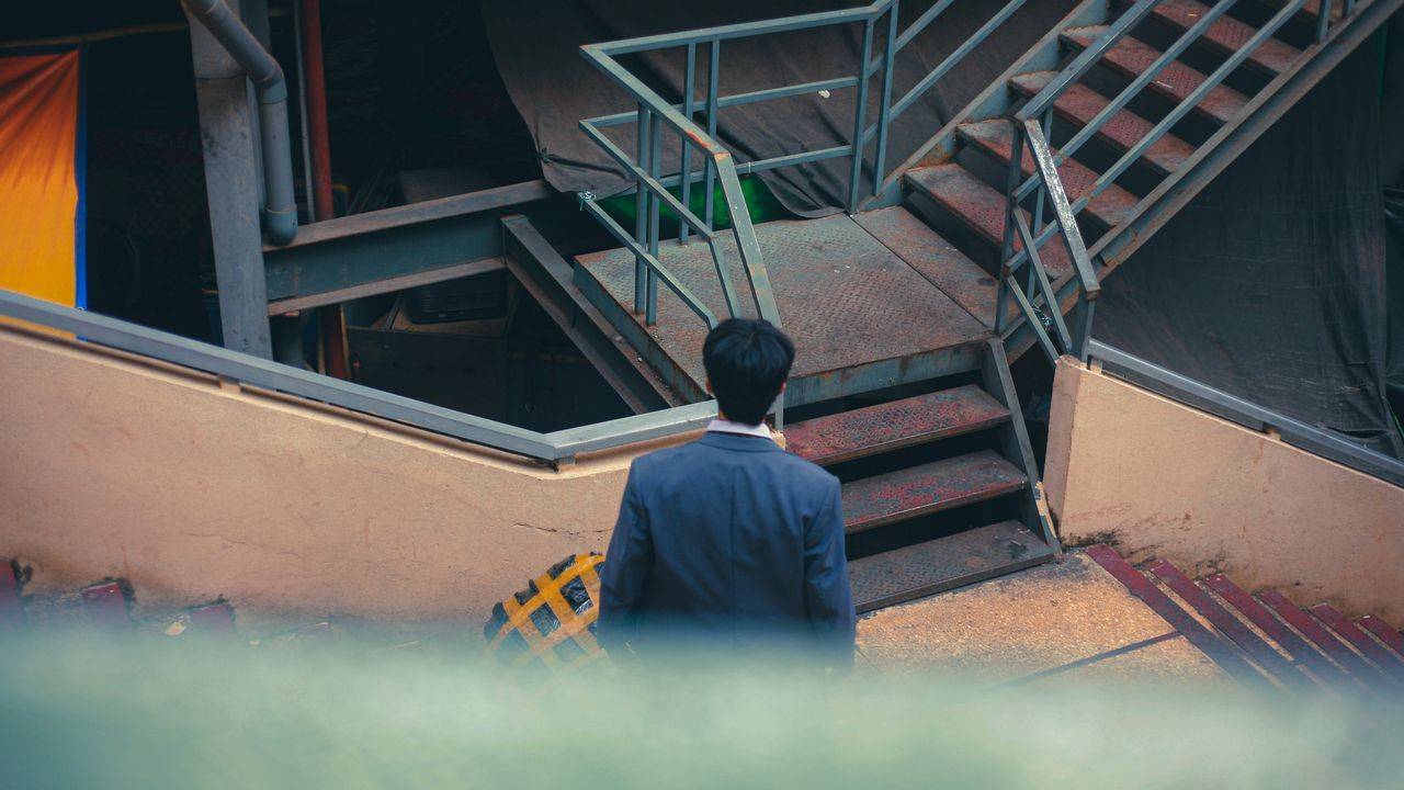 Man in a suit climbing an industrial staircase
