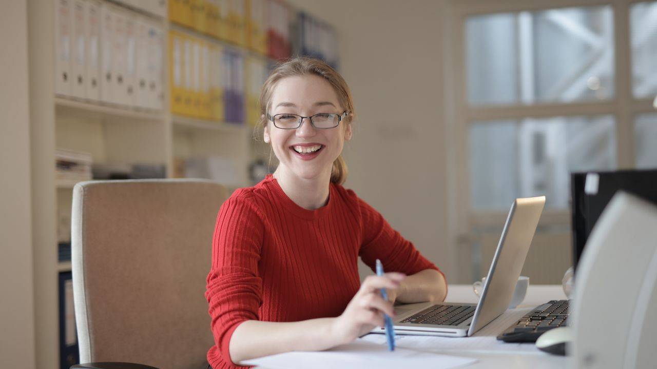 Smiling woman working at her office desk with a laptop