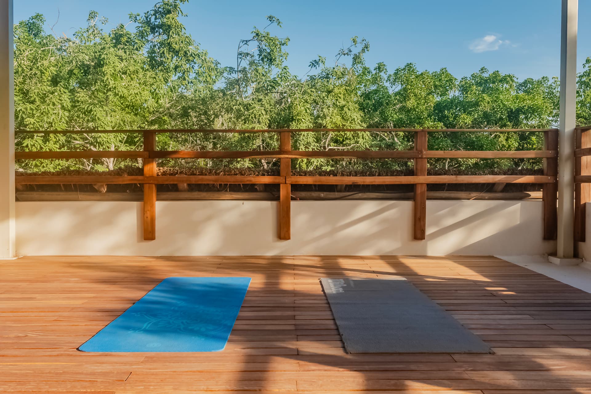 Rooftop teak yoga deck with mats facing the jungle