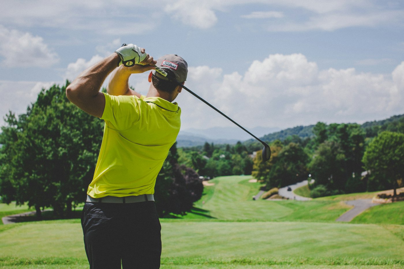 Golfer following through on a swing on a sunlit course