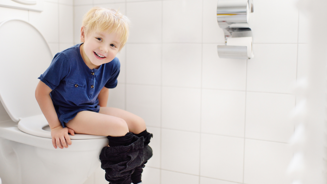 little boy smiling and sitting on the toilet