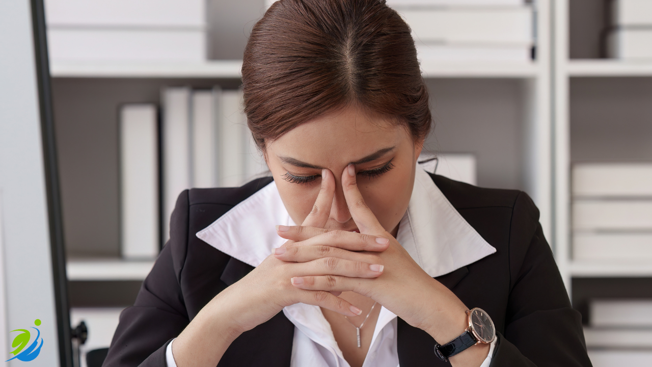 Restaurant owner sitting at a desk with eyes closed and hands pressed together in stress, representing the hidden financial and operational costs that follow workplace injuries.