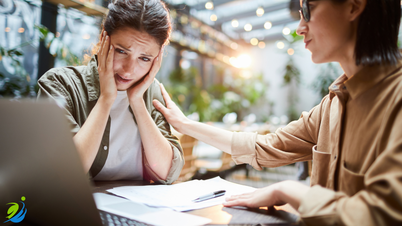 Restaurant owner reviewing paperwork with a distressed expression while a colleague offers support, representing the financial and emotional impact of a workplace injury and rising insurance costs.