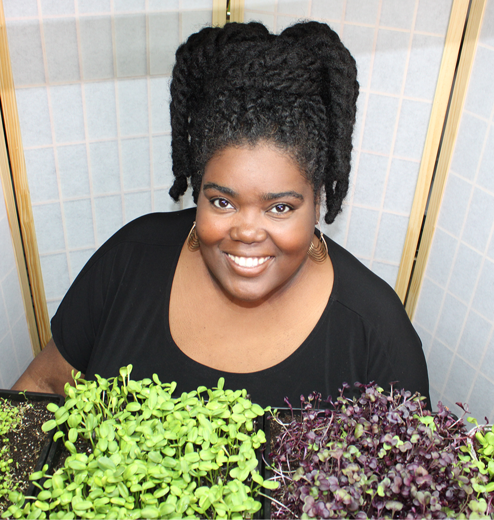Quandra presenting trays of microgreens