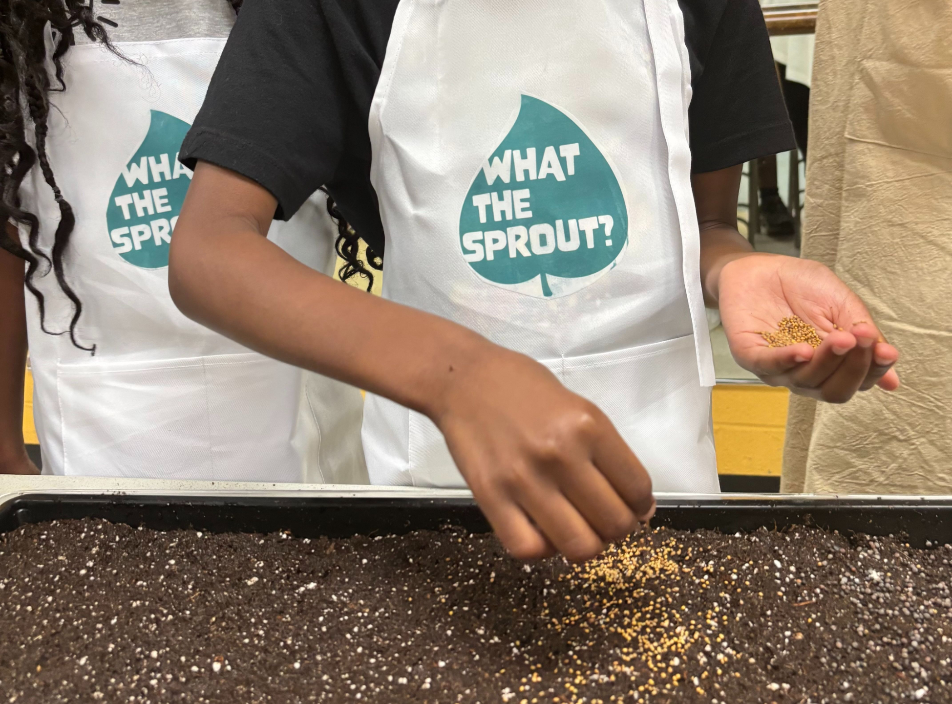 Child planting microgreen seeds in soil during a workshop