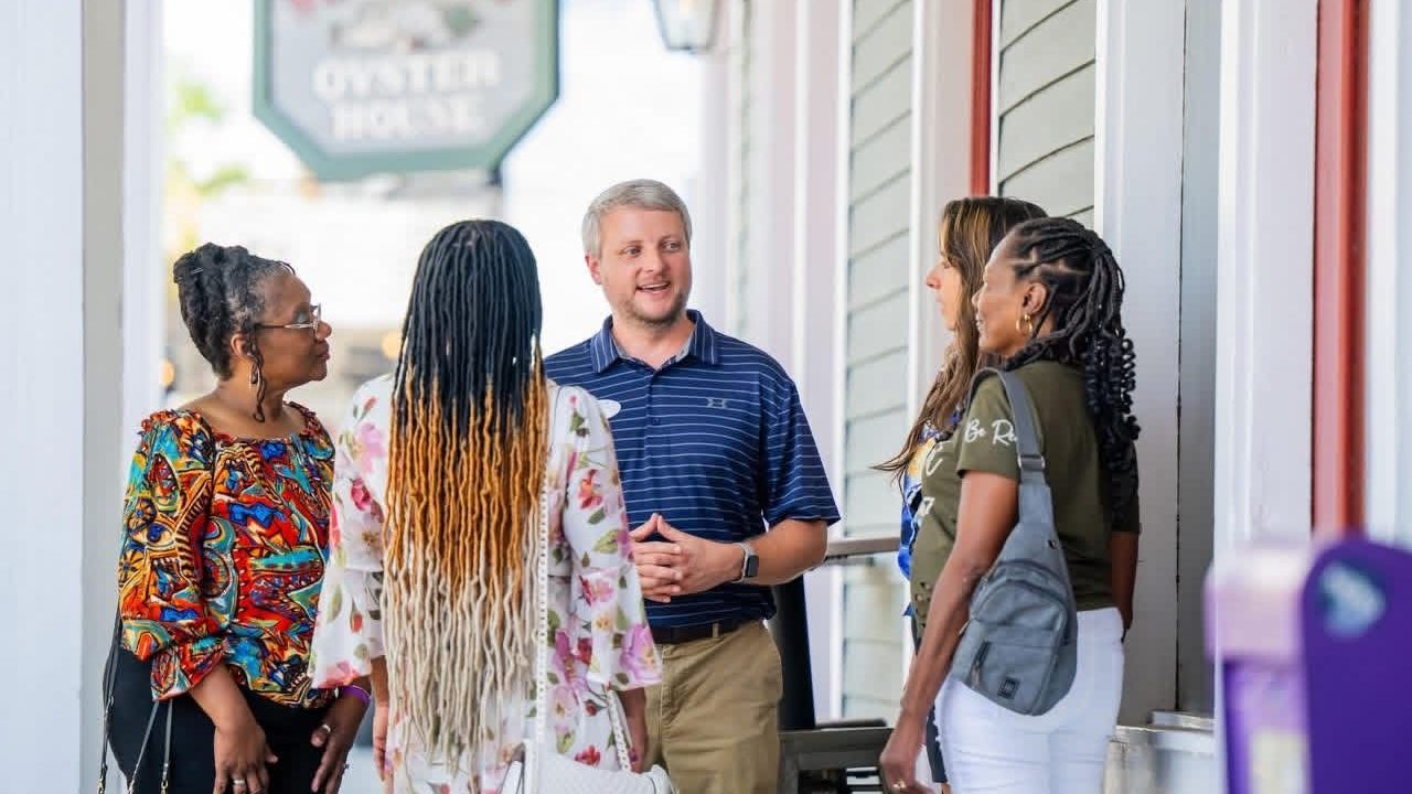 Food tour guide leading a small group of guests past local restaurants in downtown Mobile, Alabama