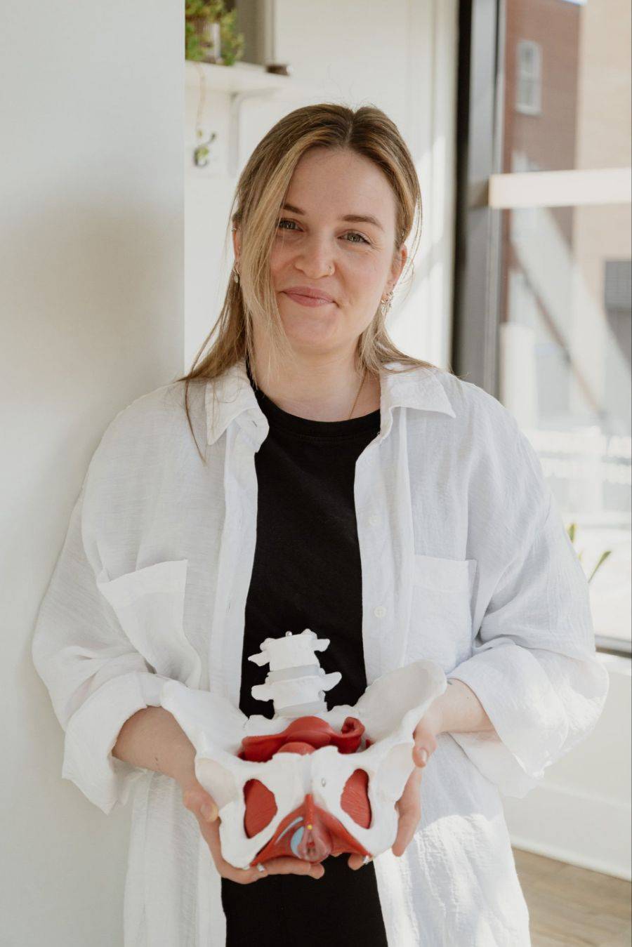 Physiothérapeute périnéale tenant un modèle anatomique du bassin – contacter CLR Physio à Montréal