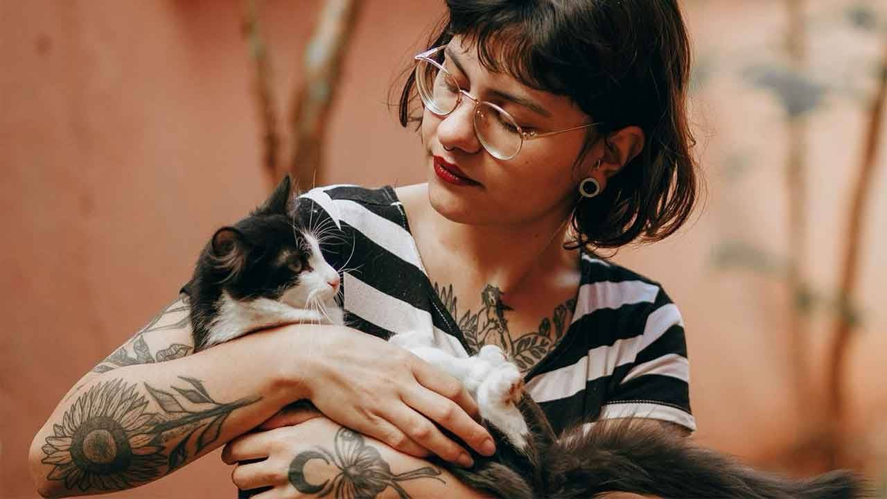 AHELP Project - Michelle Nichols blog post, Between Appointments: Why Caring for Your Ill or Aging Pet Can Feel So Hard, photo of pet caregiver cradling tuxedo black and white cat in their arms while looking at the cat lovingly.