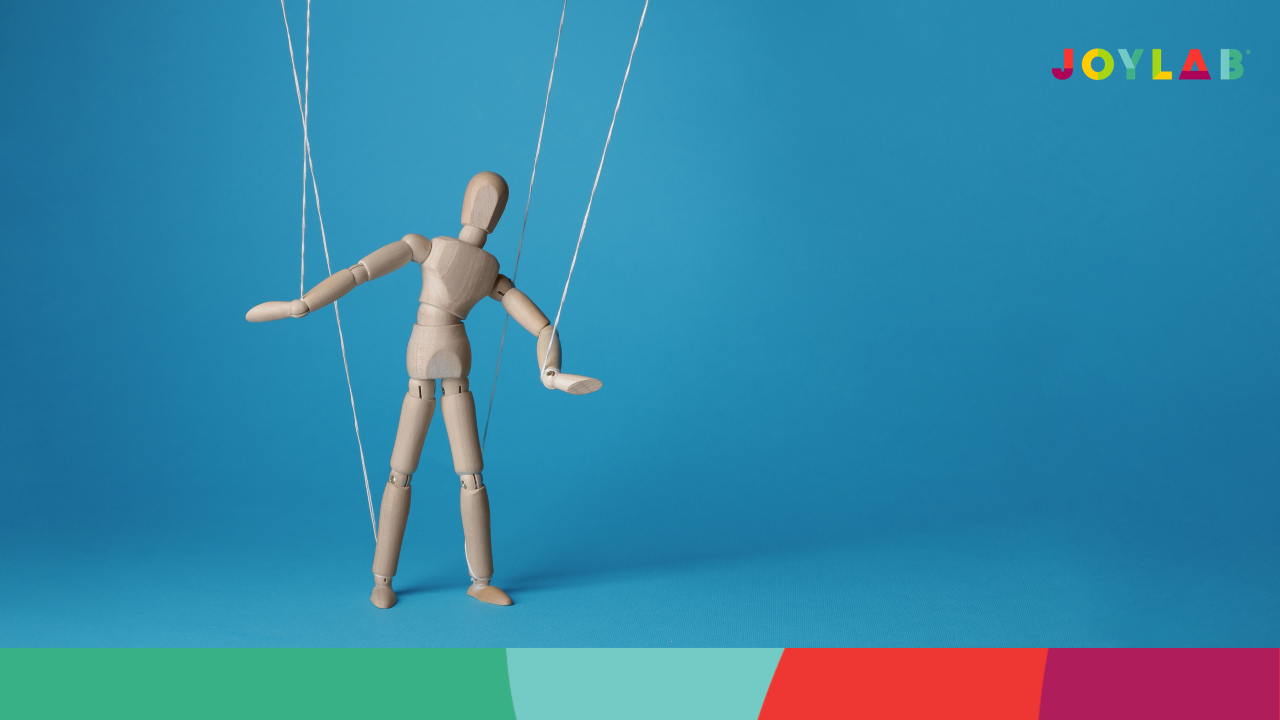 A wooden puppet being controlled by strings. Solid lue background