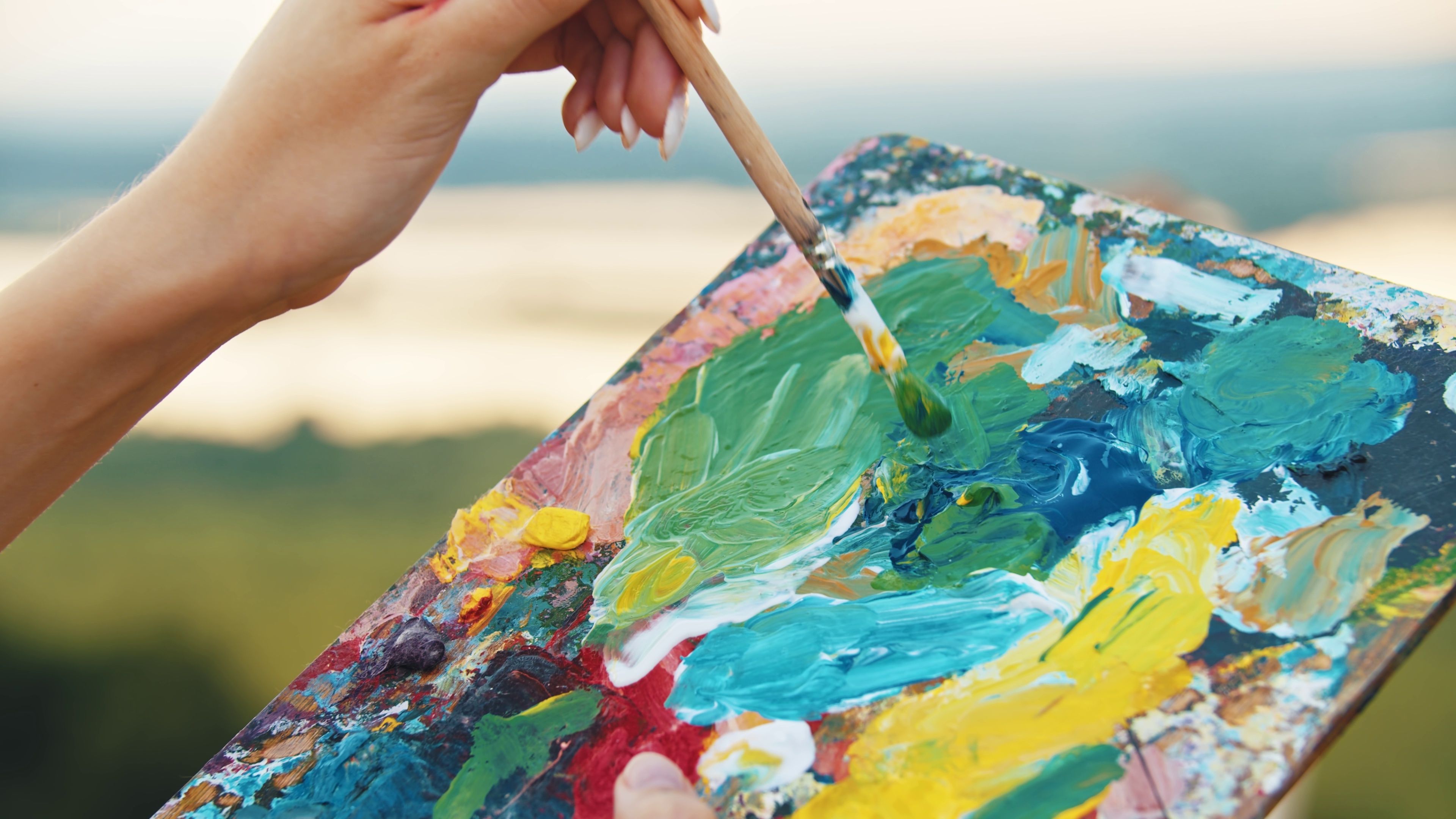 Artist mixing paint colors on a palette during a regular painting practice session.