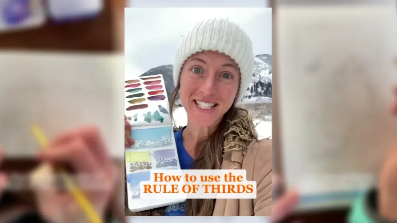 Artist Juliene holding a watercolor sketchbook with landscape studies in a snowy setting, demonstrating the rule of thirds for watercolor composition.